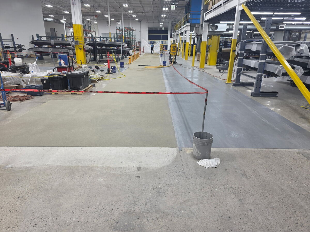 Manufacturing facility floor coating mid-installation, half coated
